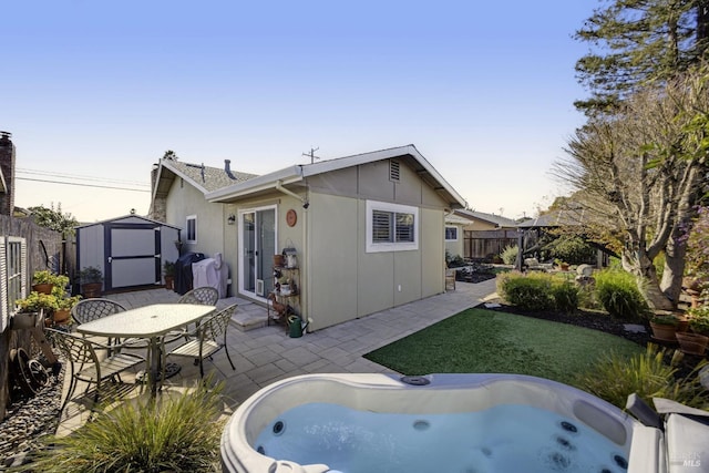 rear view of property featuring a patio, a shed, a fenced backyard, a hot tub, and an outdoor structure