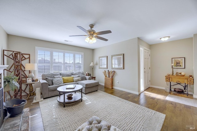 living area featuring visible vents, baseboards, wood-type flooring, and ceiling fan