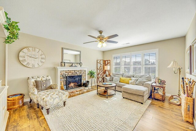 living area featuring light wood finished floors, visible vents, a fireplace, and baseboards