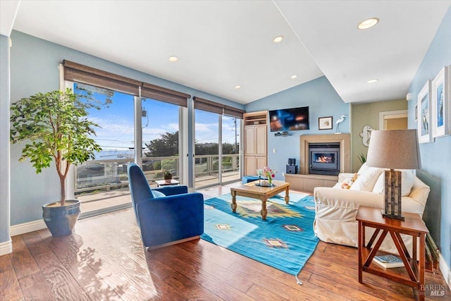 living area with a tiled fireplace, hardwood / wood-style floors, recessed lighting, baseboards, and vaulted ceiling