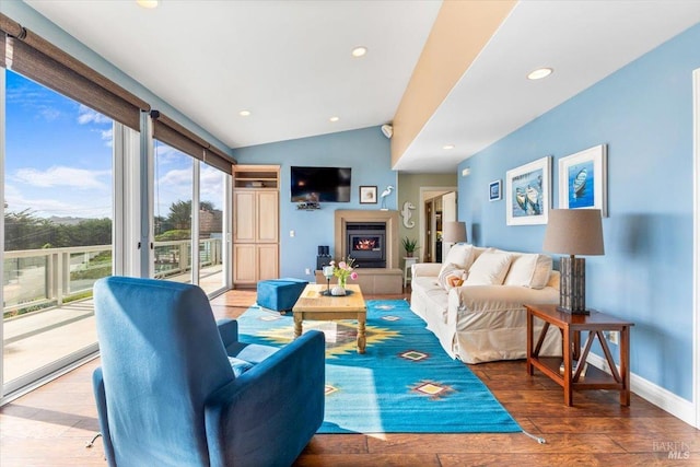 living room featuring hardwood / wood-style floors, baseboards, lofted ceiling, recessed lighting, and a lit fireplace