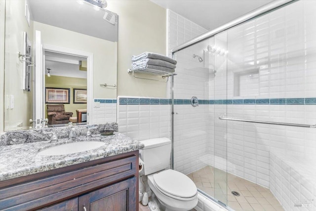 ensuite bathroom featuring a stall shower, toilet, tile walls, and vanity