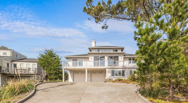 view of front facade with a chimney, stairway, concrete driveway, and a garage