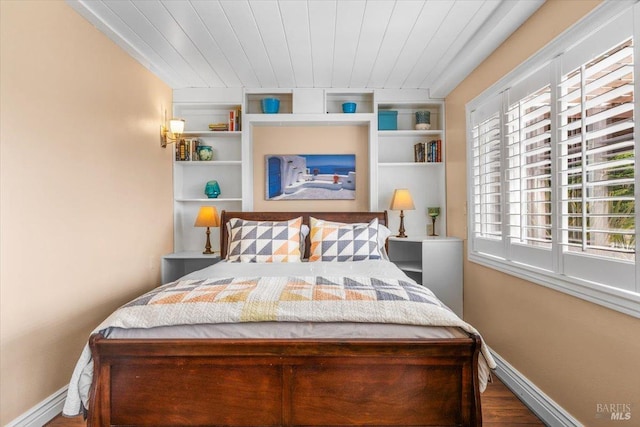 bedroom featuring wood finished floors, baseboards, and wooden ceiling