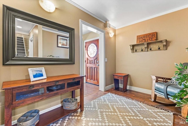 foyer entrance featuring crown molding, wood finished floors, and baseboards