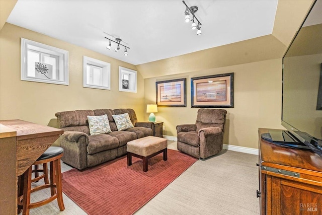 carpeted living area with baseboards, lofted ceiling, and track lighting