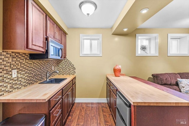 kitchen with a peninsula, a sink, butcher block countertops, dark wood-type flooring, and fridge