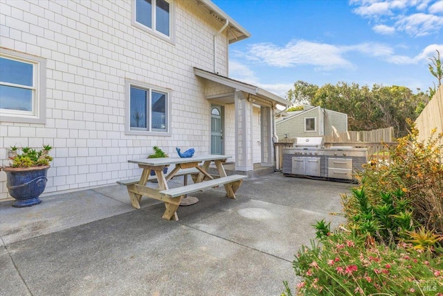 view of patio featuring outdoor dining space, exterior kitchen, grilling area, and fence