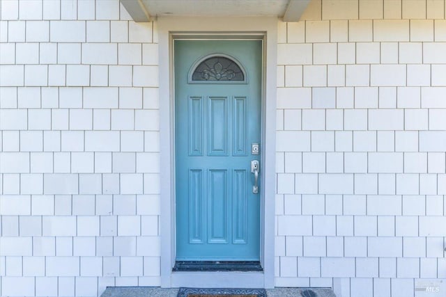 view of exterior entry with roof with shingles