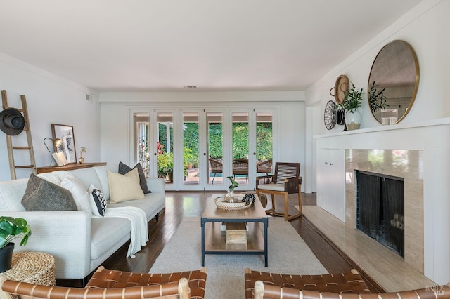 living area featuring visible vents, wood finished floors, a high end fireplace, and ornamental molding