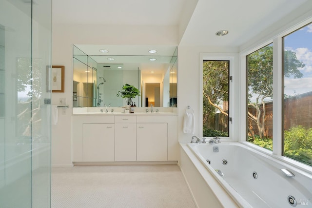 bathroom with a sink, a tub with jets, and double vanity