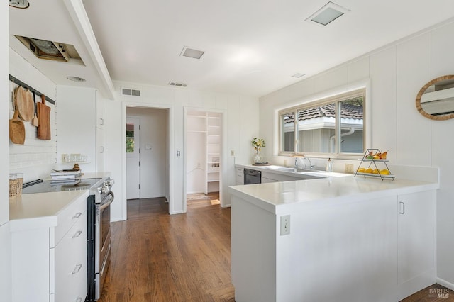 kitchen with a peninsula, dark wood-style flooring, a sink, light countertops, and electric stove