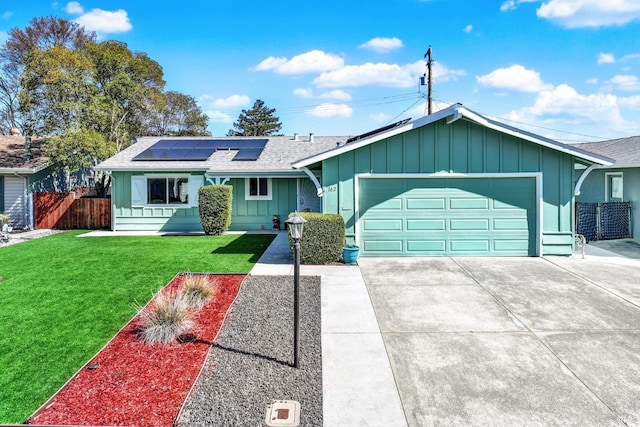 ranch-style house featuring fence, board and batten siding, a front yard, a garage, and solar panels