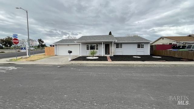 ranch-style home with concrete driveway, an attached garage, and fence