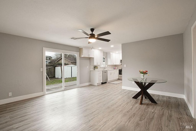 unfurnished living room with ceiling fan, baseboards, light wood-style floors, and a sink