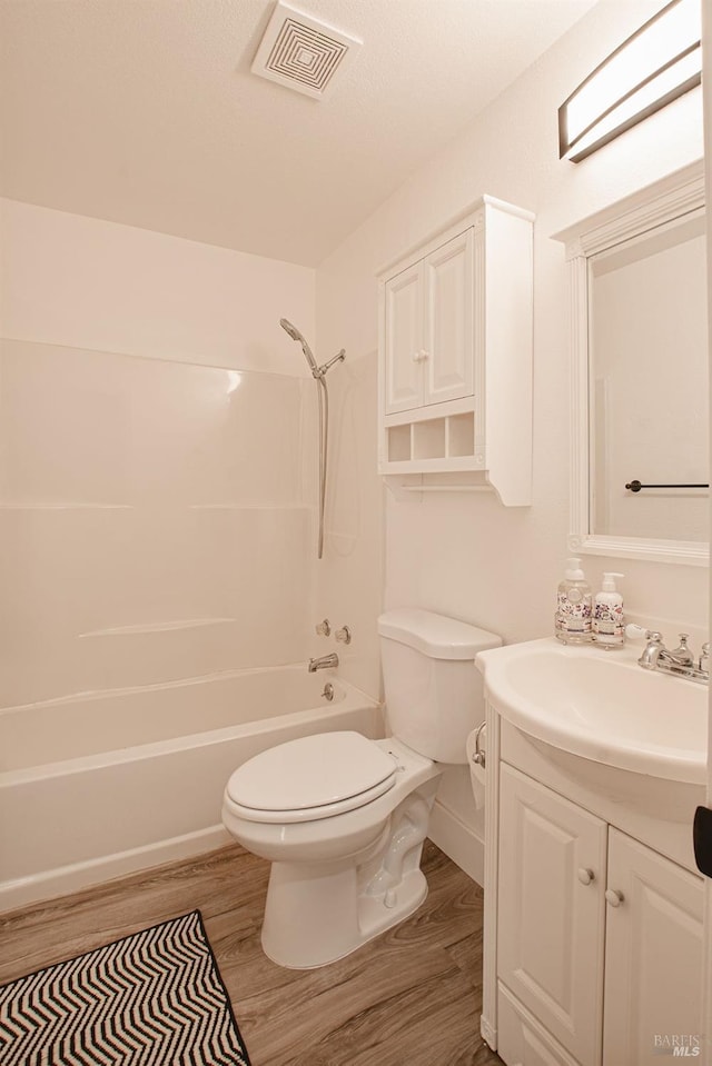 full bath featuring visible vents, toilet, bathing tub / shower combination, wood finished floors, and vanity