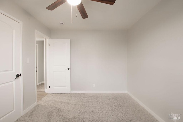 unfurnished room with baseboards, light carpet, and a ceiling fan