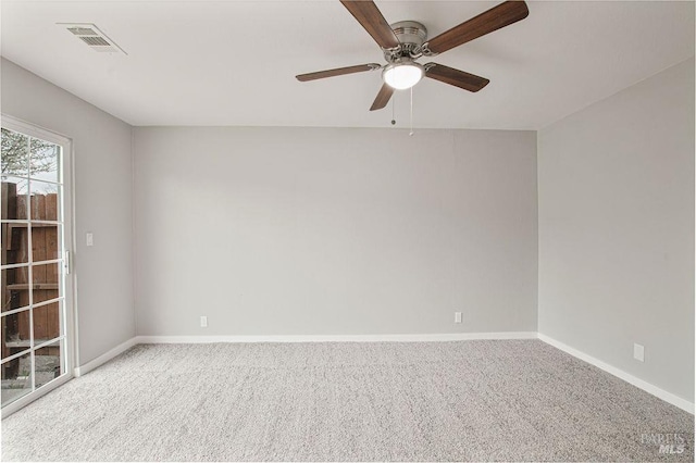 carpeted spare room featuring visible vents, baseboards, and ceiling fan