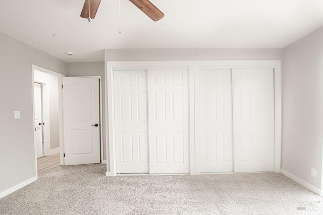 unfurnished bedroom featuring two closets, baseboards, carpet, and a ceiling fan