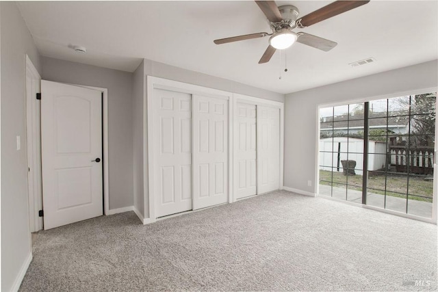 unfurnished bedroom with access to exterior, carpet, visible vents, and two closets