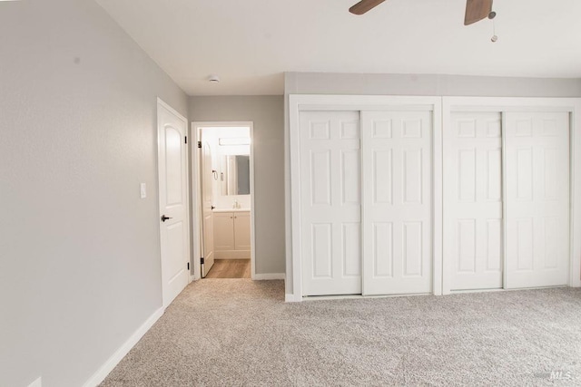 unfurnished bedroom with a ceiling fan, carpet, baseboards, and multiple closets