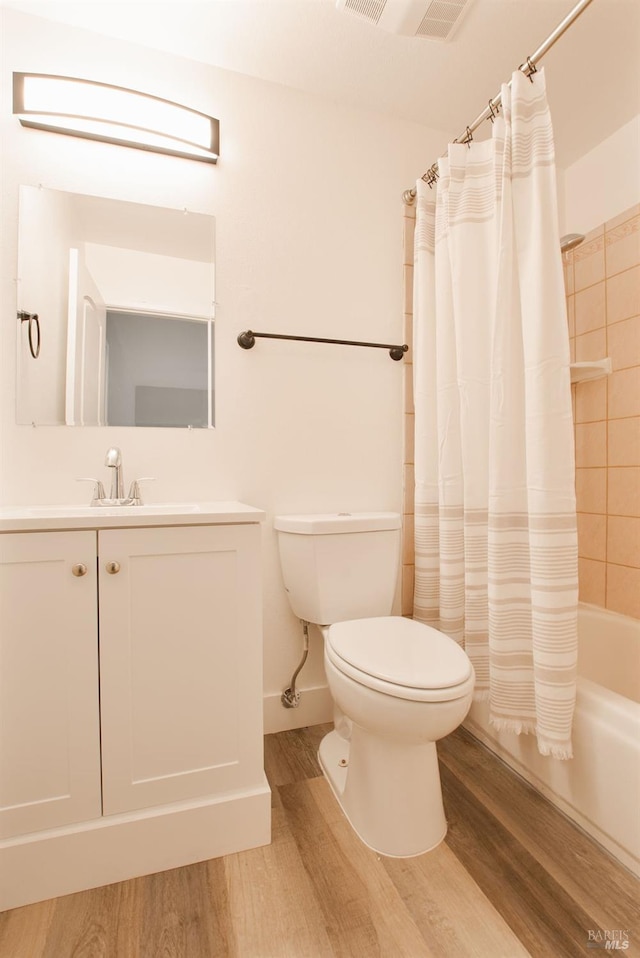 full bathroom with vanity, wood finished floors, visible vents, shower / tub combo, and toilet