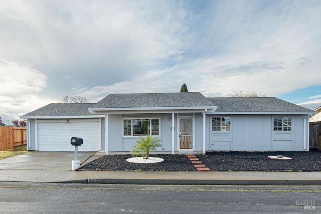 ranch-style home featuring a shingled roof, concrete driveway, an attached garage, and fence