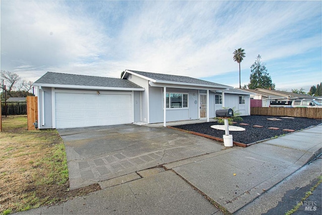 ranch-style home with an attached garage, concrete driveway, roof with shingles, and fence