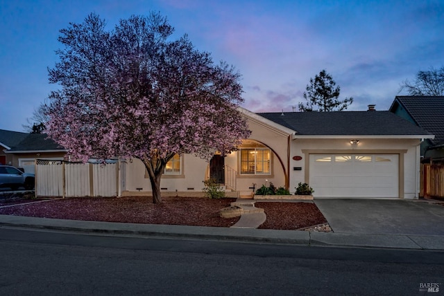 view of front facade featuring stucco siding, a garage, concrete driveway, and fence