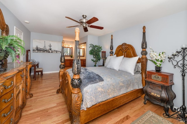 bedroom with connected bathroom, baseboards, light wood-style floors, and ceiling fan