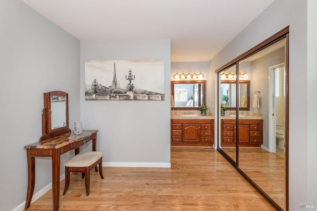 hallway featuring a wealth of natural light, light wood-style flooring, baseboards, and a sink