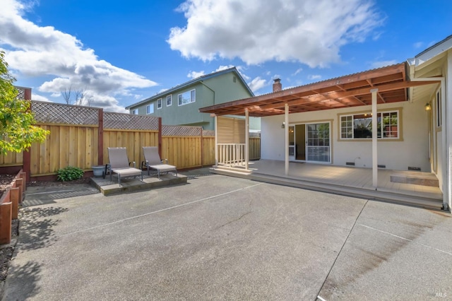 rear view of property featuring stucco siding, a patio, a chimney, and fence