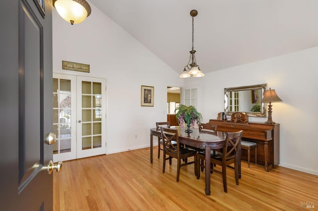 dining space with high vaulted ceiling, french doors, baseboards, and light wood-style floors