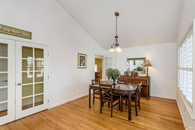 dining area with baseboards, high vaulted ceiling, and light wood finished floors