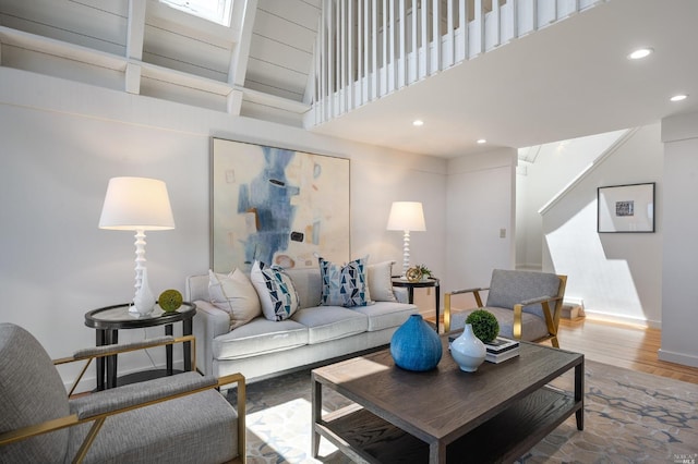 living area with a high ceiling, recessed lighting, wood finished floors, and baseboards