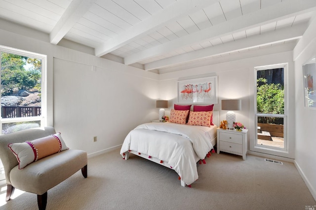 bedroom featuring beam ceiling, multiple windows, and baseboards