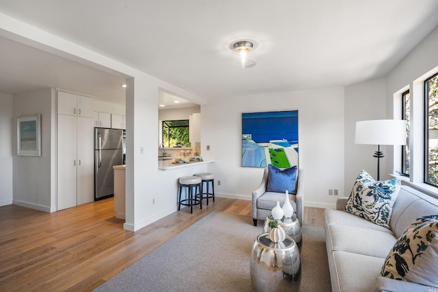 living area featuring recessed lighting, baseboards, and light wood-type flooring