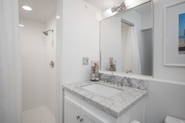 bathroom with tiled shower, toilet, and vanity