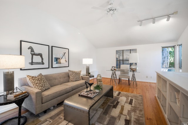 living room featuring light wood finished floors, track lighting, baseboards, lofted ceiling, and a ceiling fan