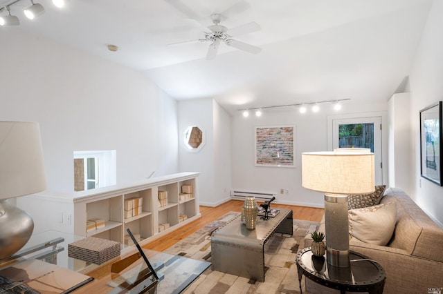 living area with baseboards, light wood finished floors, ceiling fan, vaulted ceiling, and baseboard heating