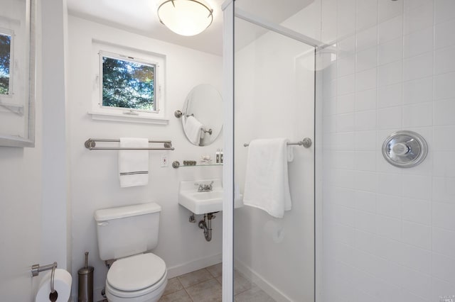 full bathroom featuring baseboards, toilet, a stall shower, tile patterned floors, and a sink