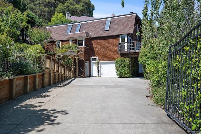 exterior space with concrete driveway, an attached garage, a gambrel roof, and a shingled roof