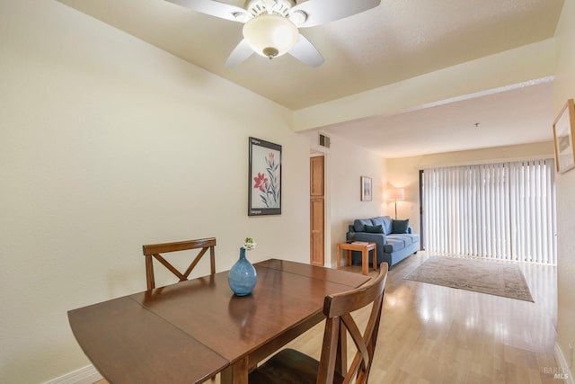 dining area featuring wood finished floors, baseboards, visible vents, beam ceiling, and ceiling fan