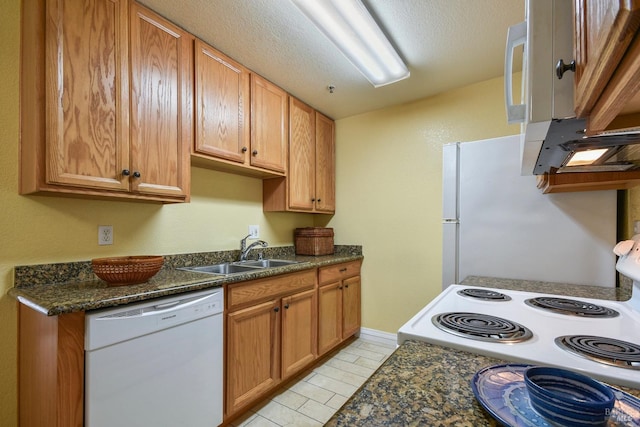 kitchen featuring under cabinet range hood, white appliances, a textured ceiling, and a sink