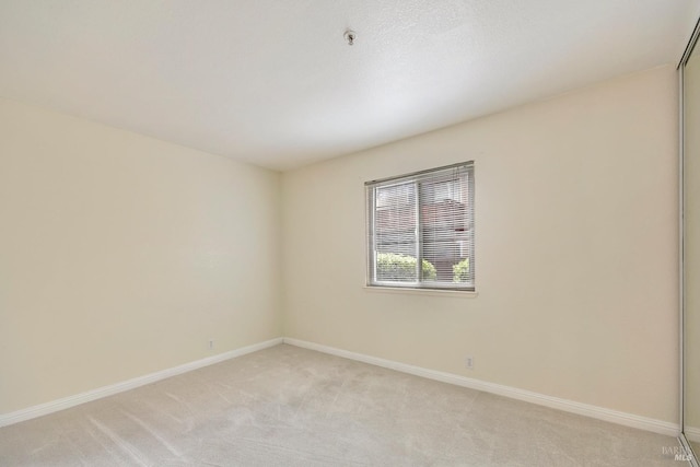 unfurnished room with light colored carpet and baseboards