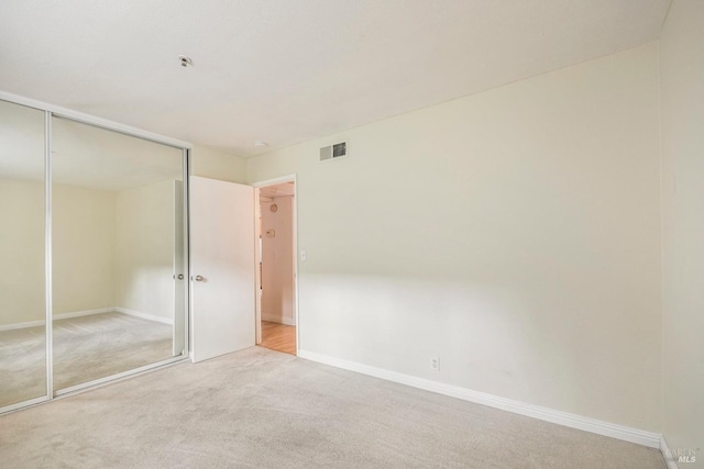 unfurnished bedroom with a closet, carpet flooring, baseboards, and visible vents