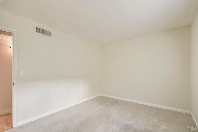 spare room with light carpet, visible vents, and baseboards