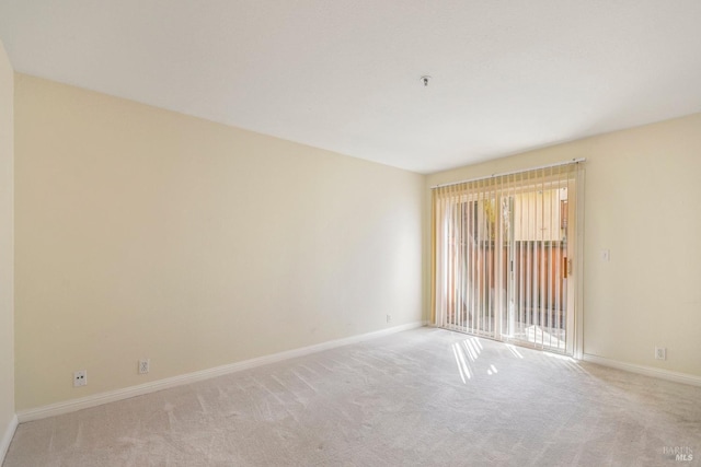 carpeted spare room featuring baseboards