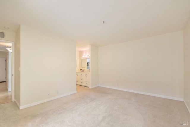 unfurnished room featuring visible vents, light colored carpet, and baseboards