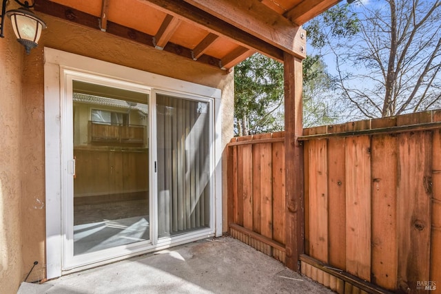 doorway to property featuring fence and stucco siding